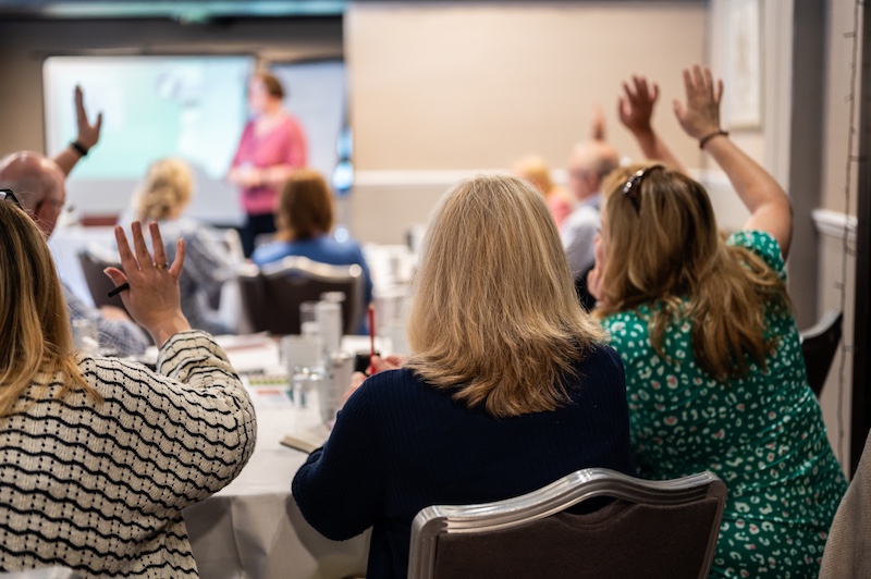 Speaking with authority: People raising their hands in a Q&A session.